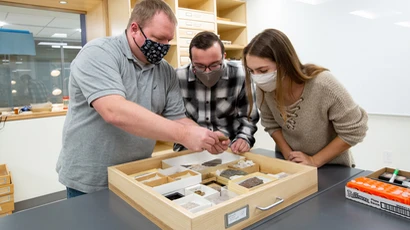 a geology class examines a rock specimen. Geology degree, geologist degree, degree in geology, major in geology.