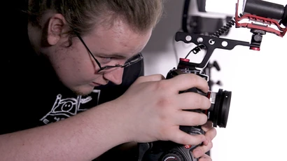 A student uses a DSLR camera to capture video in Rockefeller Arts Center, working in video arts.