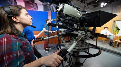 Student operates a camera in the Thompson Hall television studio. Media management degree, media management major, degree in media management. 