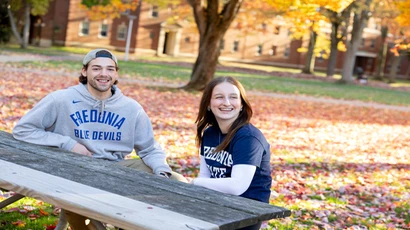 two students sit at picnic table on campus