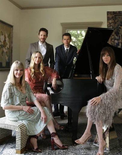 five performers gathered around a piano