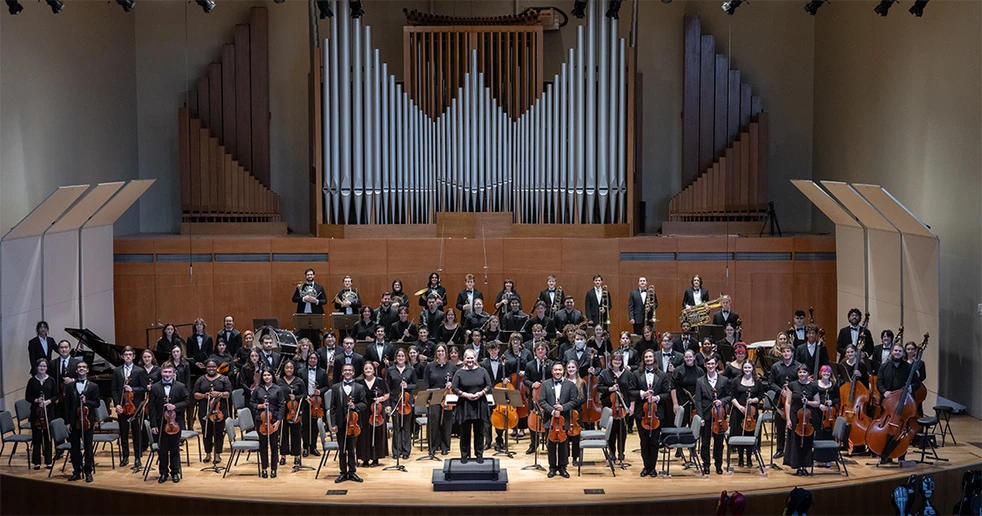 orchestra members standing on King Concert Hall stage