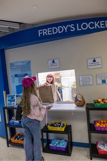 student being given a bag of food at Freddy's Locker