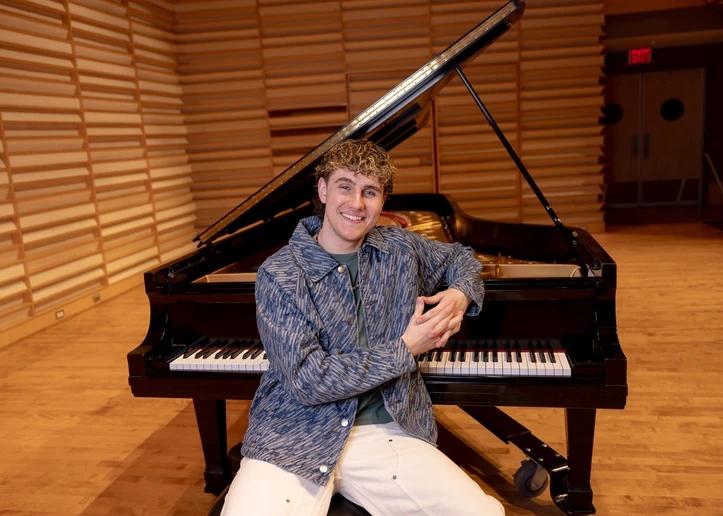 Lucas West next to the piano on stage in Rosch Recital Hall