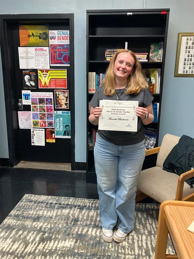 student standing holding award certificate