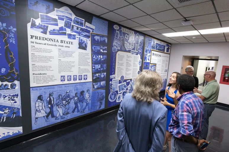 Mural artist Erin Ruffino ('19) talks about the display with members of the audience who attended the ribbon-cutting event on August 6