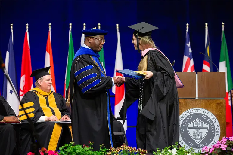 President Stephen H. Kolison Jr. congratulates a student crossing the stage.
