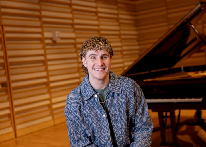 Lucas West next to the piano on stage in Rosch Recital Hall