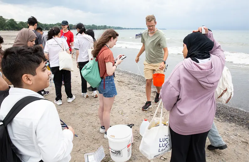 Gregory Holmberg collects a bucket of water along the Lake Erie shoreline for testing by students at Point Gratiot Park.