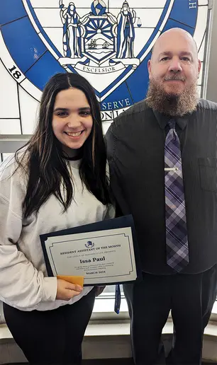 Isabelle “Issa” Paul, displaying her RA of the Month certificate, with Residence Director Jacob Steinhoff.