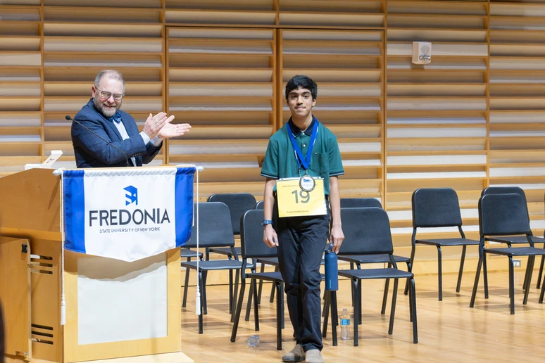 Adhrit Chowdhury receives his medallion and is congratulated by Emcee Joe Dan Harper.