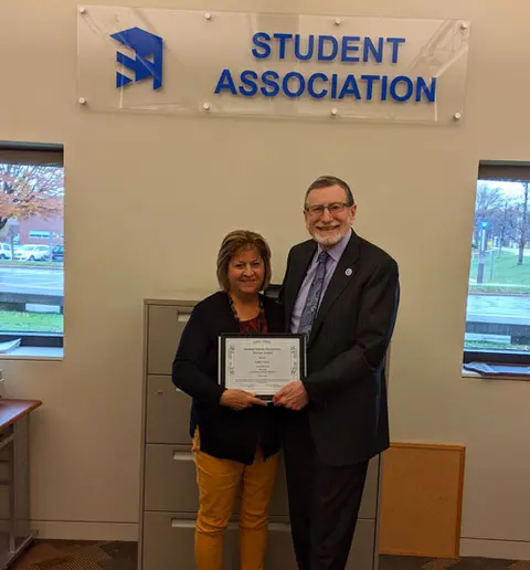 Interim President Dennis Hefner presents the Barbara Saletta Meritorious Service Award to Kathy Carrus in the SA office.