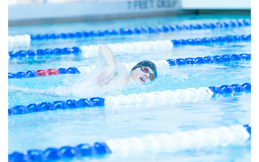 man swimming freestyle by Travis Bernhard