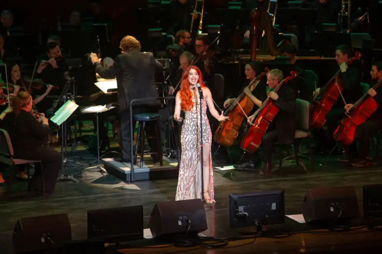 singer with orchestra in concert hall