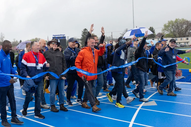 alumni walking through ribbon at start-finish line at Fredonia outdoor track
