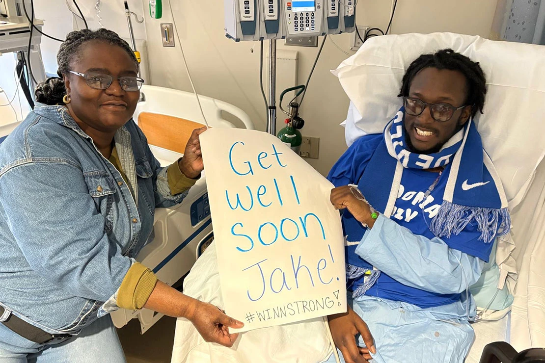 Jacob Winn (right) and his mother hold up a sign made for him by Fredonia students during his recovery