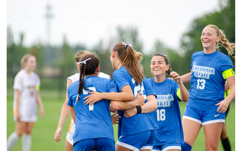 women soccer players celebrating on the field by Riley Olson