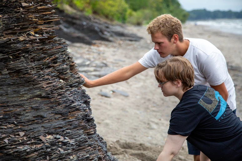 Fredonia students examining a rock formation on the shores of Lake Erie