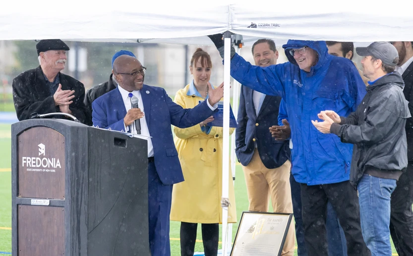 president kolison acknowledges former coach ulrich who waves to crowd while under canopy