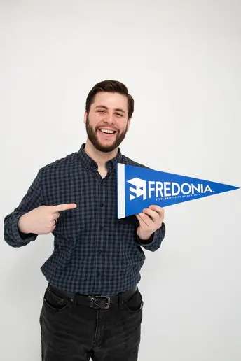 Luca Vukelic, a master's student in music, smiling with a FRED pennant