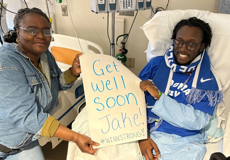 Jacob Winn and his mother, Valerie McBride, hold up sign of support from Fredonia students