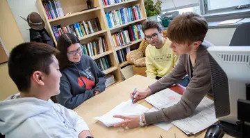 Fredonia students meeting with a math professor in her office. Fredonia's 12-to-1 student to faculty ratio ensures your professor will always know your name, and student faculty mentoring is common