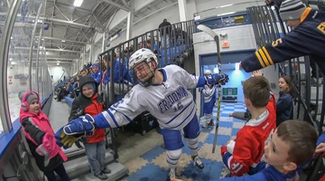 Fredonia hockey player high fiving a young fan