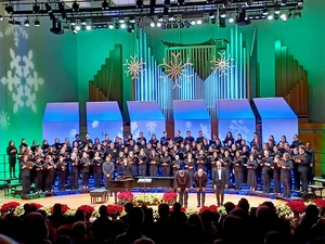 chorus and directors on stage in King Concert Hall with holiday decorations