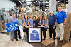 administrators present local businesses with signs and memorabilia