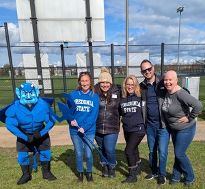 Blue devil mascot with people outdoors
