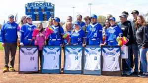 senior softball players with framed jerseys and their families 