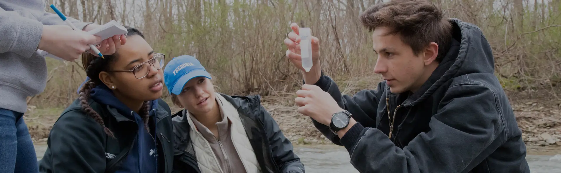 bio students working with a professor studying a water sample