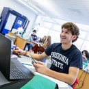 Student smiling in front of a laptop in a lab