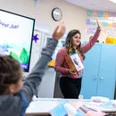 Fredonia student teacher in a classroom raising her hand