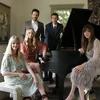 five performers gathered around a piano