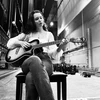 student seated and playing a guitar