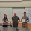 two students with certificates standing with faculty member