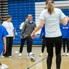 women and girls kicking soccer balls in gymnasium
