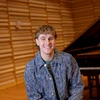 Lucas West next to the piano on stage in Rosch Recital Hall