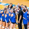 volleyball players in a huddle with coach by Travis Bernhard