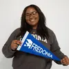 Harmony Buchanan smiling and holding a Fredonia pennant 