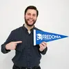 Luca Vukelic, a master's student in music, smiling with a FRED pennant 